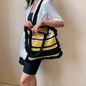 Handmade crochet tote bag with black and yellow stripes featuring elegant ruffled edges