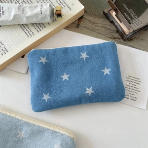 Close-up of denim star print cosmetic pouch with metal zipper and lifestyle props