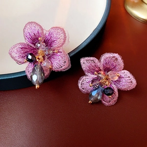 Dettaglio degli orecchini a fiore in tulle viola con perle di cristallo e ricamo curato