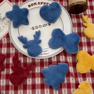 Close-up of colorful plush Christmas tree ornaments and DIY star patches on a table