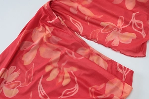 Détail du tissu en maille rouge avec motifs floraux et couture délicate à bord ondulé