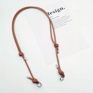 Detail of adjustable brown leather bag strap with silver metal spring clips and knots