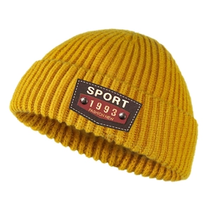 Detail of ginger yellow knitted beanie with brown leather sport fashion patch and rivets