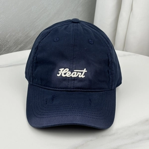 Detail of navy blue baseball cap featuring white Heart embroidery and distressed torn fabric