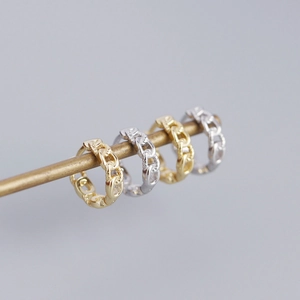 Macro view of interlocking chain link earrings in polished gold and silver metal finishes