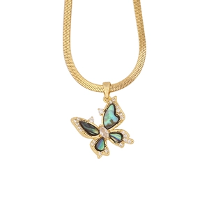 Macro shot of gold butterfly pendant with iridescent shell wings and sparkling zircon accents