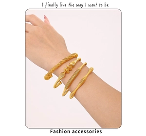 Detail of four gold-plated stainless steel spring wire spiral cuff bracelets on wrist