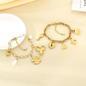 Detailed close-up of golden charm bracelets with heart, key, and shell motifs on satin