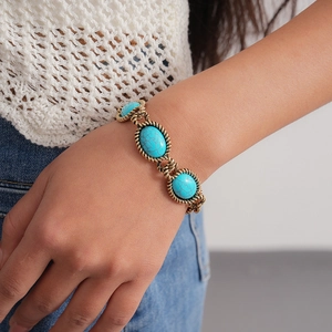 Detail of vintage gold twisted chain bracelet with oval turquoise stones on a wrist