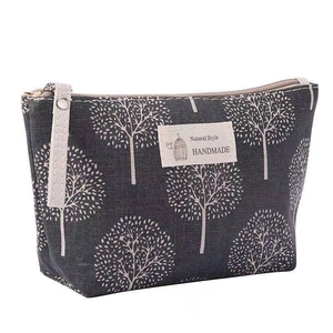 Close-up of dark grey canvas cosmetic bag with white tree prints and handmade label