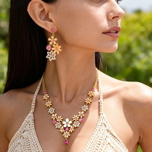 Elegant gold flower jewelry set with pink crystals worn by a model in nature