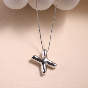 Macro shot of silver letter X pendant with balloon style design and sleek box chain