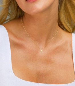 Detail view of a gold initial A necklace on a female neck with a sleek minimalist design