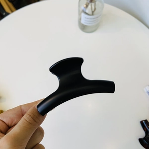 Close-up of a large matte black shark hair claw clip with elegant curved lines