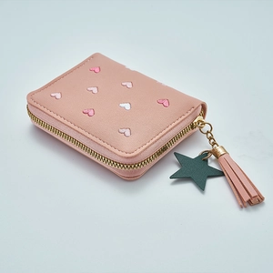 Close-up of pink PU wallet with heart embroidery, gold zipper, and tassel star charm