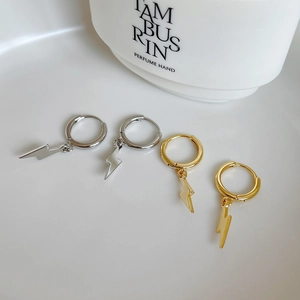 Detailed close-up of gold and silver lightning bolt charms on hoop earrings