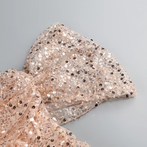 Detailed view of champagne pink sequins and mesh fabric on a stylish cocktail dress