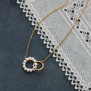 Elegant gold double interlocking circles necklace with white pearls on dark navy background
