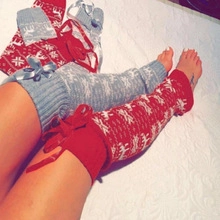 Detail of knitted Christmas stockings in red and grey with reindeer patterns and bows
