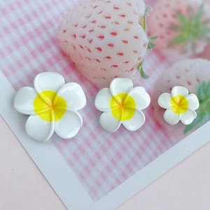 Three white resin plumeria flowers with yellow centers on a pink strawberry background