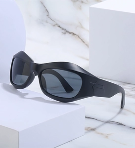 Detail of matte black wraparound Y2K sunglasses with wide temples on marble surface