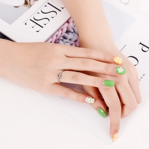 Detail view of a minimalist knot-shaped silver ring worn on a finger with stylish nails