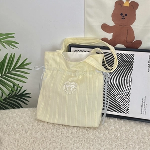 Dettaglio borsa shopper in velluto a coste giallo con ricamo in pizzo e lacci in nastro