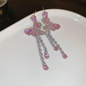 Macro detail of butterfly tassel earrings with pink zircons and drop-shaped gems