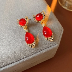 Close-up of vintage gold bow earrings with red teardrop gems and sparkling rhinestones
