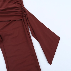 Detail view of the ruched side and long streamer of the dark red slim-fit jumpsuit