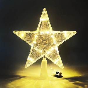 Macro detail of a lighted transparent star tree topper with warm LED glow and battery box