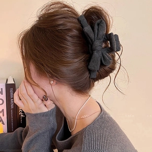Détail de la pince à cheveux à nœud en tissu gris foncé montrant la matière en laine