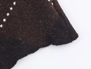 Close-up of diamond pattern knit fabric with fuzzy texture and white dot weaving
