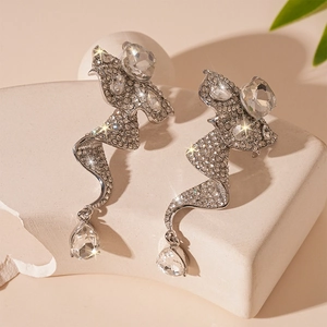 Sparkling silver spiral drop earrings with crystals on a stone display base