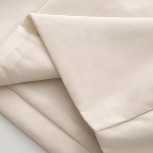 Close-up of soft beige knitted fabric texture with elegant layered folds