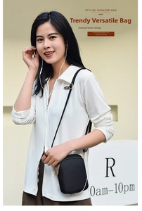 Close-up of black crossbody phone bag with gold zippers worn by a female model