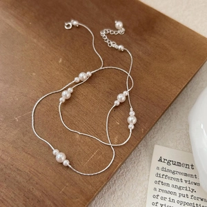 Minimalist 925 sterling silver pearl necklace displayed on a rustic dark wood background