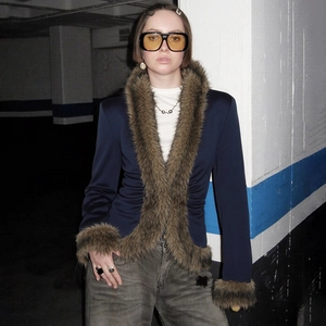 Detail showing the deep V-neck and fluffy brown faux fur trim on the navy blue jacket