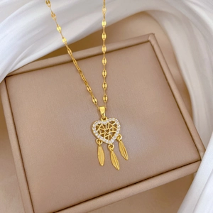 Dettaglio della collana acchiappasogni dorata con cuore e piume sulla seta