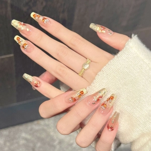 Macro-detail van kistvormige roze nagels met gouden glitters en amberen edelstenen