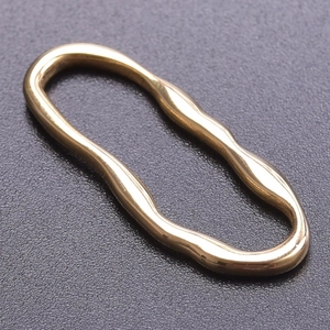 Nahaufnahme des goldenen wellenförmigen Rings mit glatter Metallstruktur auf grauem Grund