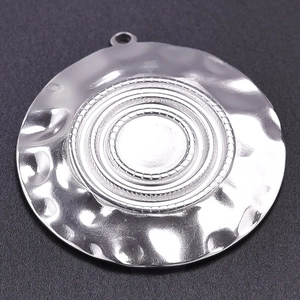 Macro detail of round 304 stainless steel pendant with hammered texture and concentric circles