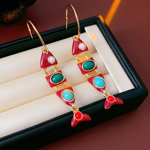 Vue macro de boucles d'oreilles poisson vintage en émail rouge et pierres colorées