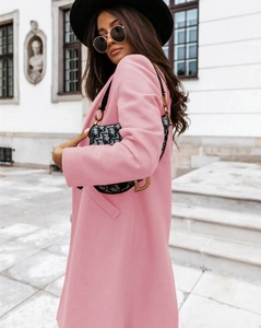 Detail of pink long lapel wool coat with buttons shown in an urban street setting