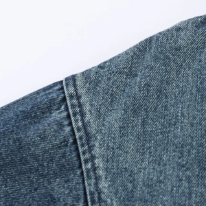Macro shot of double-reinforced shoulder seams on a blue washed denim jacket