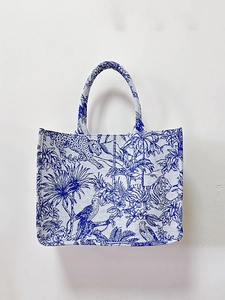 Detailed close-up of tiger and leopard embroidery on white and blue tote bag fabric