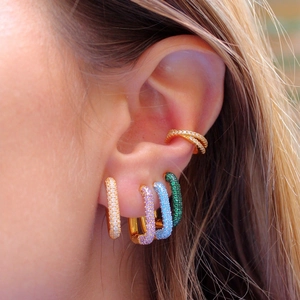 Close-up of gold ear cuffs set with colorful zircon stones worn on the ear detail