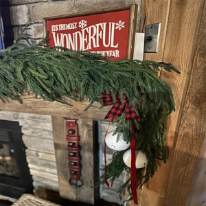 Detail of Christmas PE pine garland with buffalo plaid bow and festive wooden sign