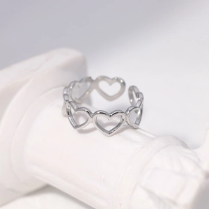 Macro view of silver hollow heart-shaped stainless steel ring on a white marble pedestal