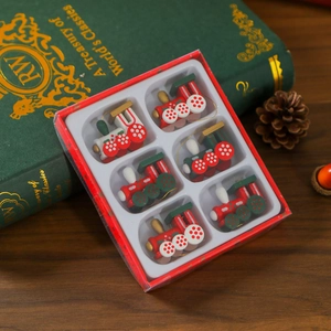 Detail view of 6-piece wooden Christmas train ornaments in a red gift box on a vintage book